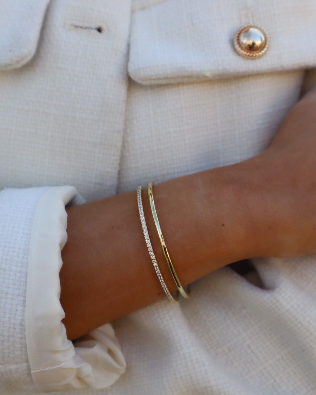 Two gold bangles stacked on the wrist