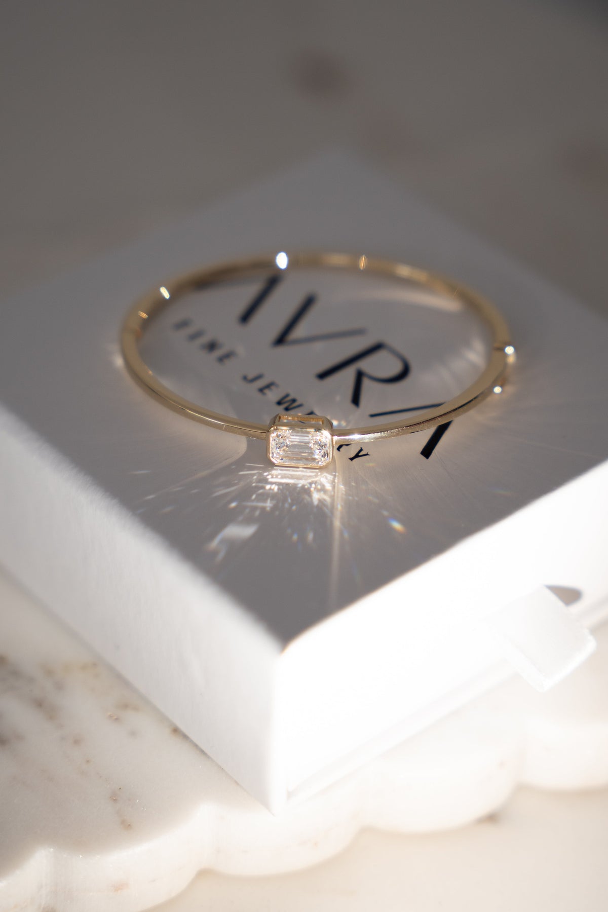 The Emerald Diamond Bangle resting on the AVRA box